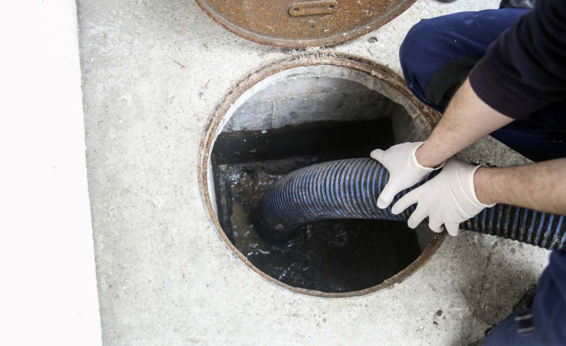 Worker cleaning sludge from a septic tank